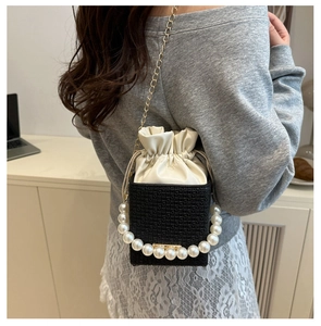 Detail of mini bucket bag with pearl handle, golden chain strap, and drawstring closure