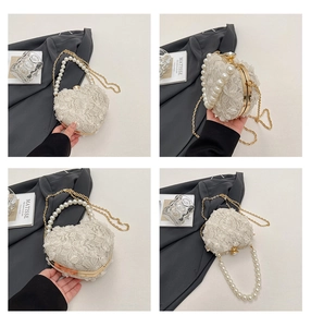 Detail of heart-shaped lace evening bag with pearl handle and golden chain straps