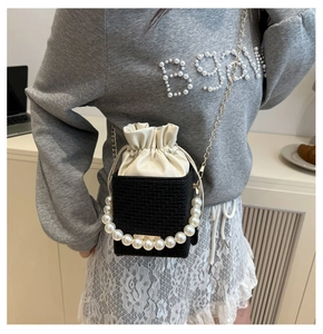 Detail of tweed bucket bag featuring large pearl handle and gold chain shoulder strap