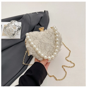 Detail of heart-shaped lace evening bag with pearl handle and rhinestone clasp