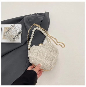 Close-up of heart-shaped lace evening bag with white pearls and gold metal chain