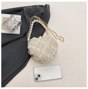 Close-up of heart-shaped lace bag with pearl handle and golden chain detail