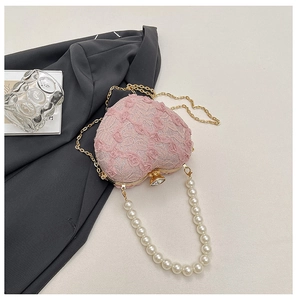 Macro shot of heart-shaped lace evening bag with 3D rose texture and pearl handle