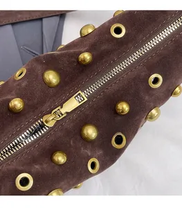 Close-up of vintage brown suede bag with gold rivets and smooth metal zipper details