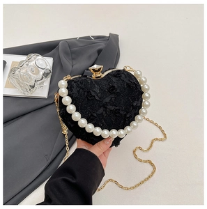 Detailed close-up of heart-shaped lace bag with pearl handle and gemstone clasp