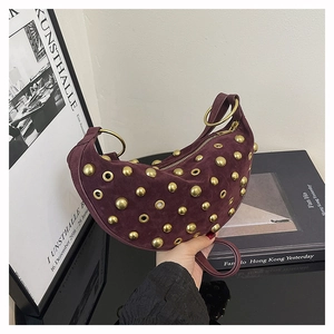 Detail of dark burgundy suede moon bag with golden studs and metal ring handle