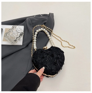 Detailed close-up of heart-shaped lace evening bag with pearl handle on grey suit fabric