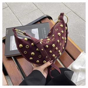 Detail of dark burgundy suede crescent bag with gold stud rivets and metal ring hardware
