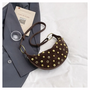 Detail of dark brown suede crescent bag with gold studs and large metal rings decoration