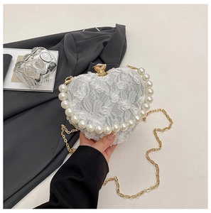 Close-up of a heart-shaped evening bag with white lace floral fabric and pearl trim