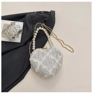 Close-up of white heart-shaped lace bag with pearl handle and golden chain detail