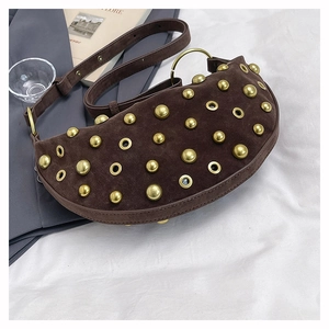 Detail of dark brown suede crescent bag featuring gold rivets and metal ring handle