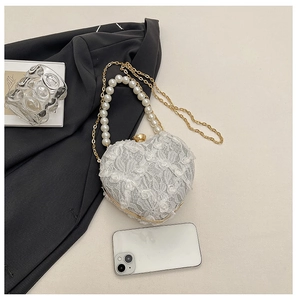 Detailed macro view of heart-shaped lace evening bag with pearls and golden chain