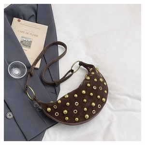 Close-up of brown suede moon bag with golden metal studs and vintage eyelet details