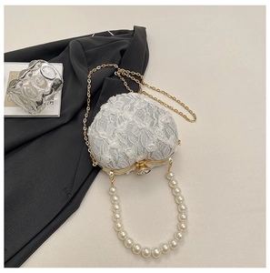 Detail of white heart-shaped lace evening bag with pearl handle and gold chain