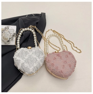 Detail view of heart-shaped lace evening bags with pearl handles and gold chains