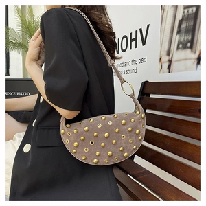 Detail of retro punk hobo bag featuring golden rivets and metal grommets on grey suede