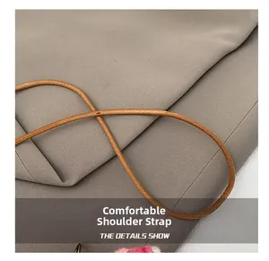 Detail of comfortable brown leather shoulder strap with smooth texture on grey fabric