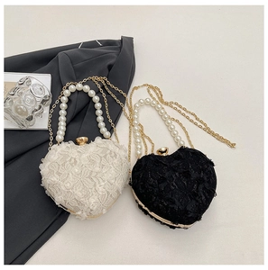 Detail of heart-shaped lace evening bags with pearl handles and gold chain straps
