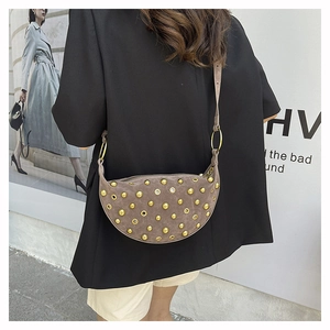 Detail of brown suede crescent bag featuring golden rivets and eyelets on shoulder