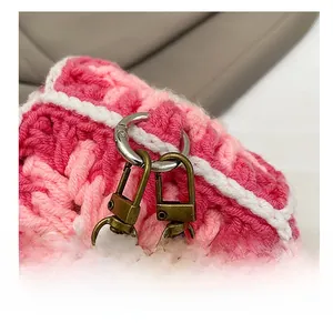 Macro detail of pink hand-knitted mini crossbody bag showing premium metal hardware hooks