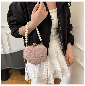 Detail showing the pink lace heart-shaped bag with pearl handle and floral accents