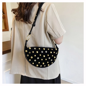 Detail of black punk shoulder bag with gold metal rivets and eyelet decorations