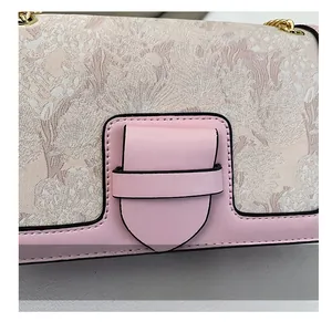 Detail of pink leather handbag with intricate embroidery texture and gold chain strap