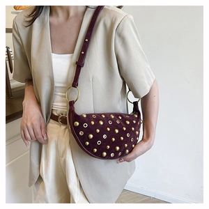 Detail of burgundy crescent bag with gold studs and metal eyelets on soft faux suede texture