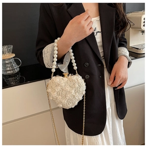 Detailed shot of the white lace heart-shaped bag with pearl handle and metal chain strap