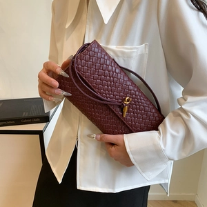 Sac baguette tressé bordeaux avec boucle en métal doré porté par un mannequin