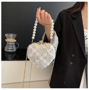 Detail of heart-shaped lace evening bag with pearl handle and 3D floral embellishments