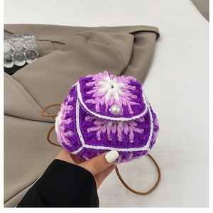 Detailed close-up of handmade purple knit mini crossbody bag with pearl button accent