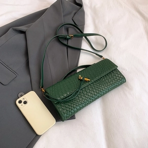 Sac bandoulière en cuir tressé vert forêt avec fermoir nœud doré sur surface blanche