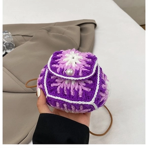Detail of hand-knit mini bag with purple flower pattern, pearl button, and thin brown strap