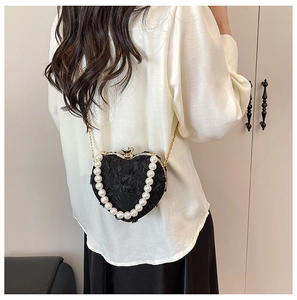 Close-up of heart-shaped black lace evening bag with pearl handle and floral details