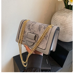 Close-up of grey textured flap bag with metallic chain strap and feather pattern detail