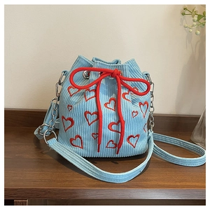 Close-up of heart embroidery pattern on light blue corduroy bucket bag texture