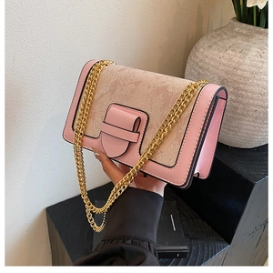 Pink and beige jacquard shoulder bag with gold chain strap held in hand for size context