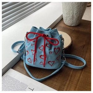 Detail of light blue corduroy bucket bag with red heart embroidery and drawstring