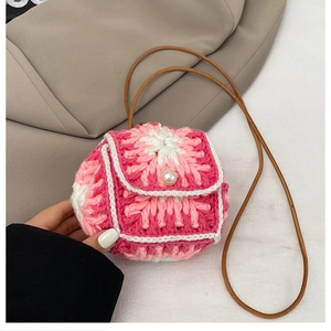 Detailed close-up of handmade pink and white crochet mini bag with pearl button