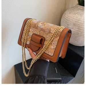 Close-up of vintage brown leather handbag with artistic print and thick gold chain straps