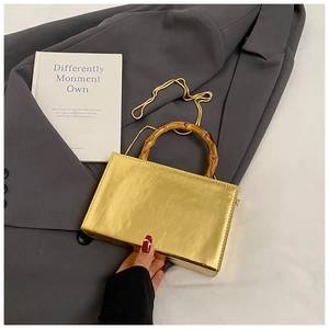 Detail of gold mirror box bag featuring vintage bamboo handle and slim chain strap