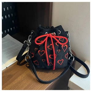 Detail of black corduroy bucket bag with red heart embroidery on a wooden table