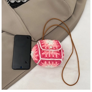 Detail of a mini knitted crossbody bag with pearl button next to a smartphone