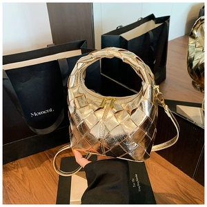 Détail d'un sac hobo doré tissé avec texture matelassée et fermetures éclair doubles