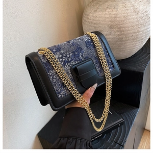 Close-up of vintage floral embroidery with black leather trim and gold chain strap