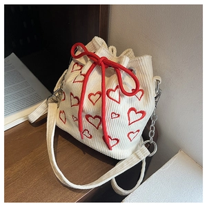 Detail of white corduroy bucket bag featuring red heart embroidery and rope drawstring