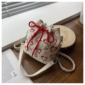 Detail of cream corduroy bucket bag featuring red heart embroidery and drawstring closure