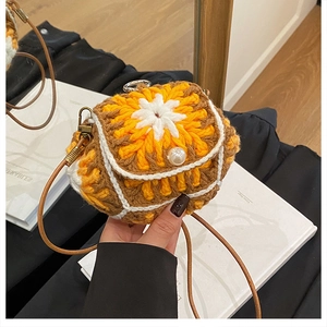 Close-up of handmade floral crochet mini bag featuring a pearl button and leather strap